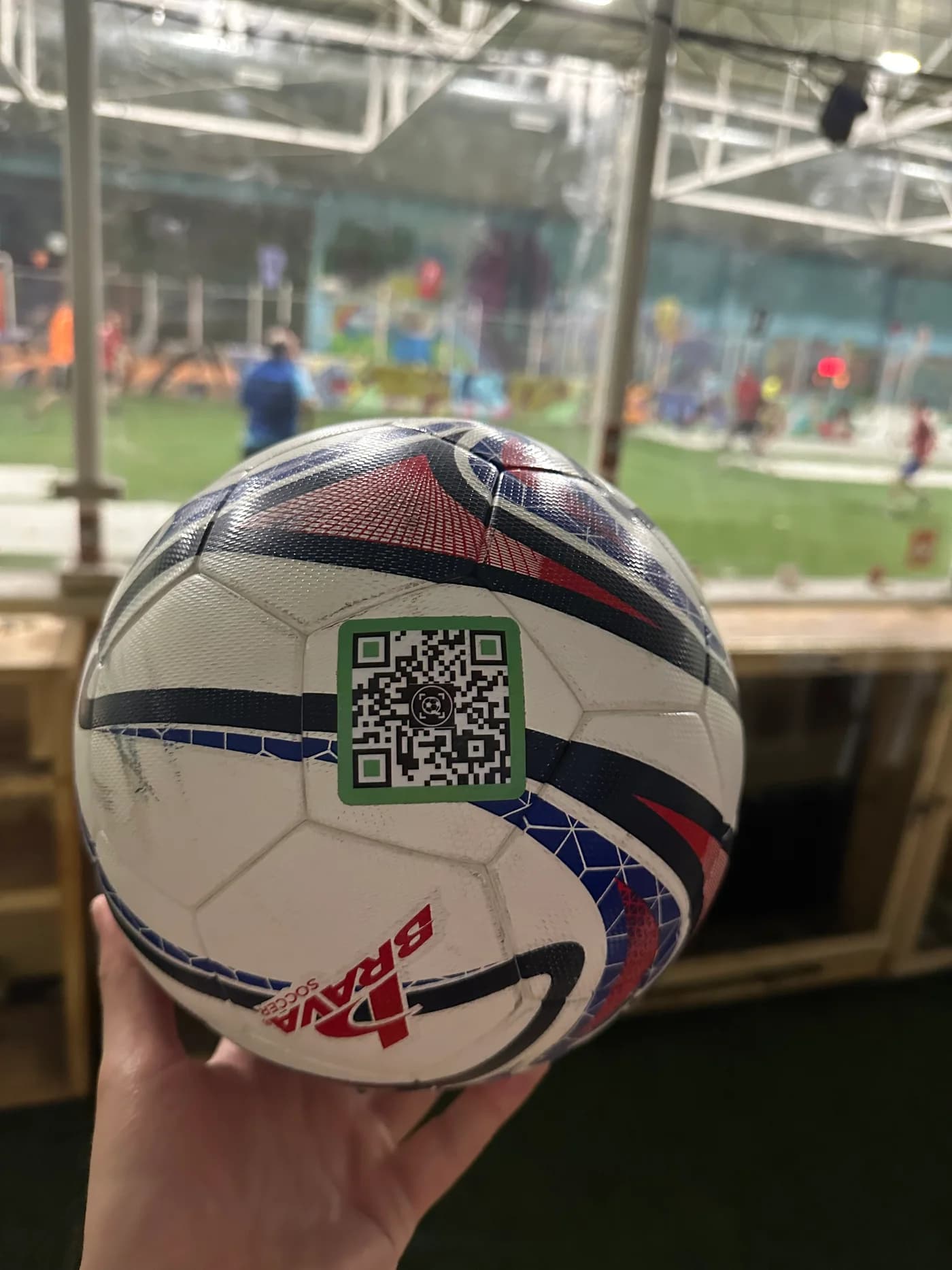 A soccer ball with a visible SoccQR return label at an indoor venue
